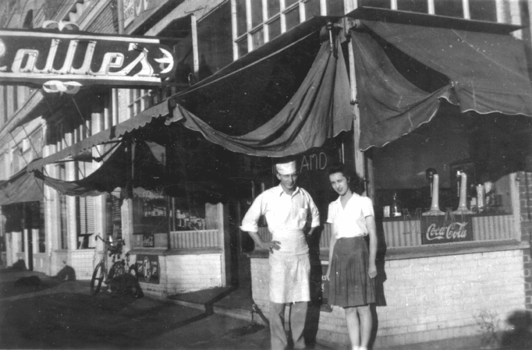 man and woman stand outside Rollie's cafe