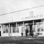 three men stand outside business building