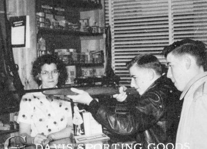 men look through rifle scope in sporting goods store